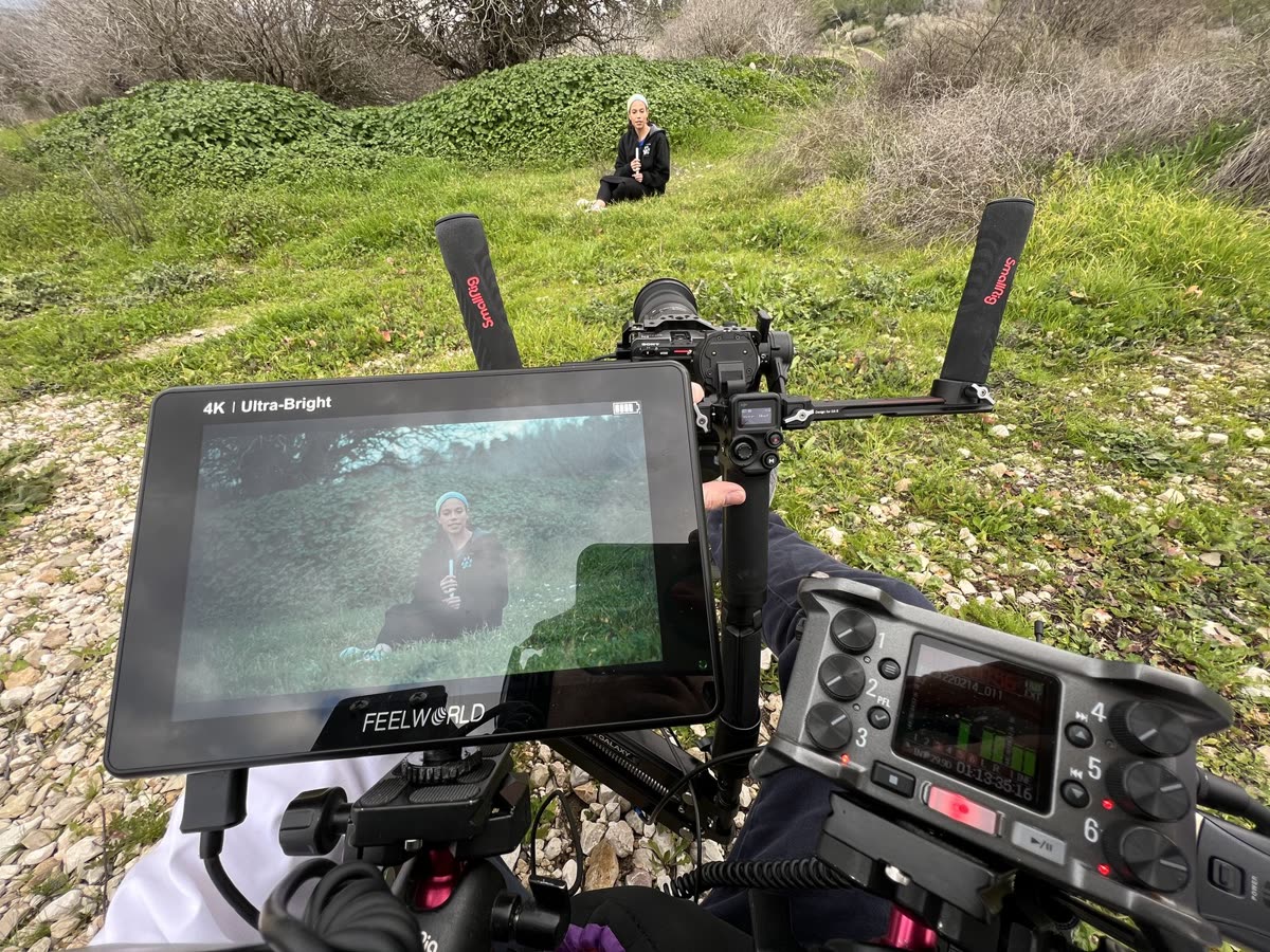 The monitor showing a man sitting in a green field