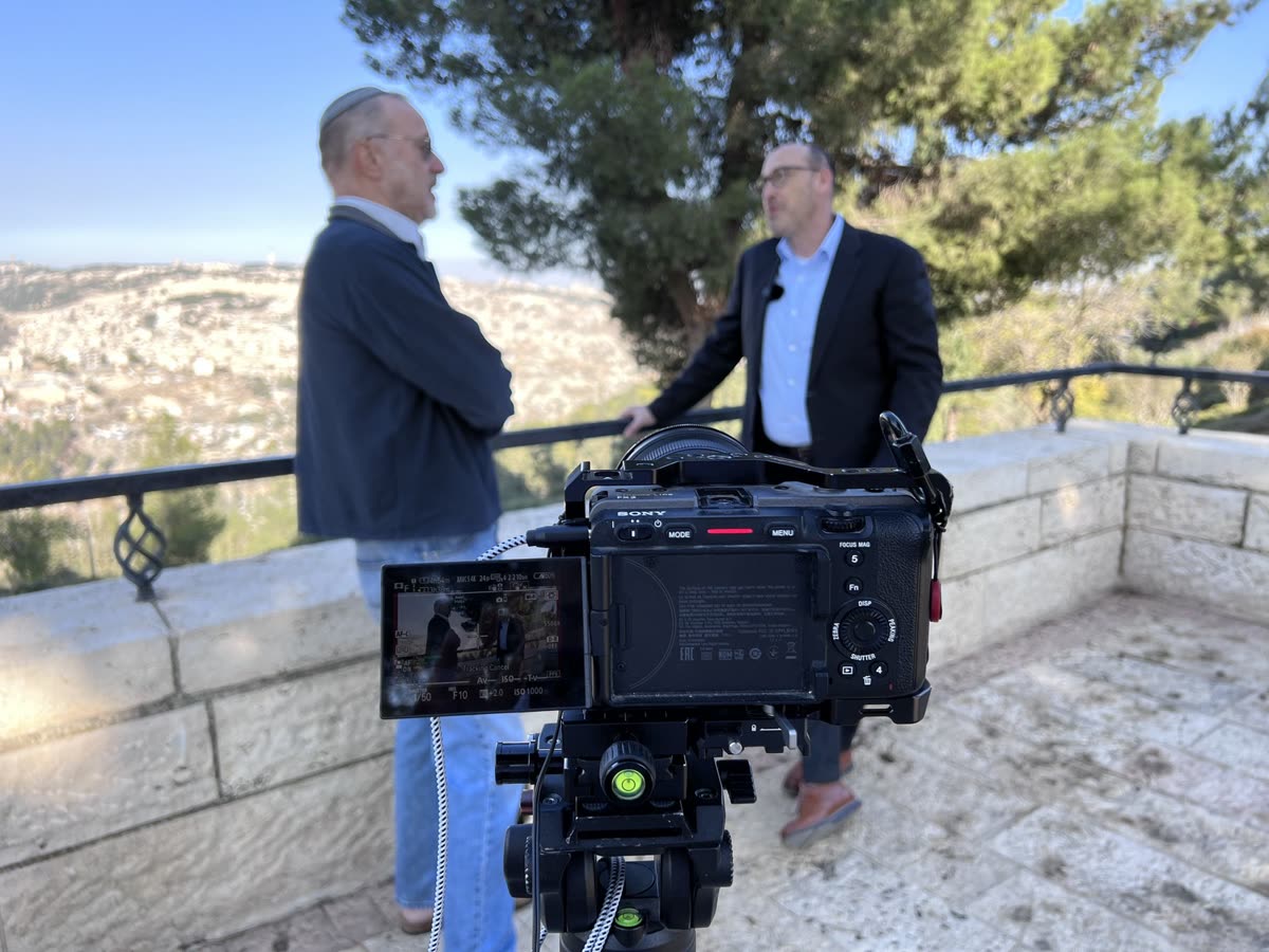 Two men talking on a stone terrace, the camera in front of them
